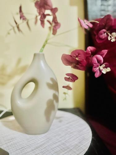 a white vase sitting on a table with flowers at Maun self-catering unit in Maun