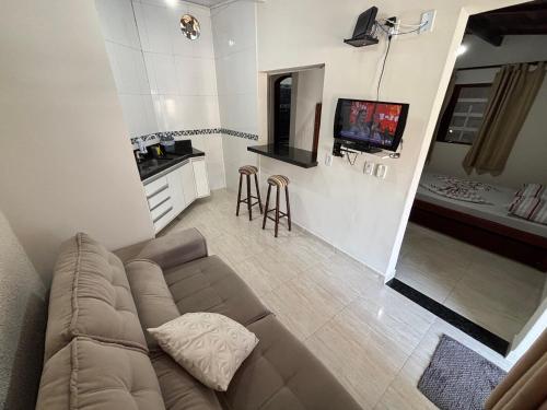 a living room with a couch and a tv at Pousada da Árvore in Boicucanga