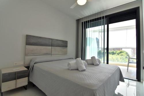 a white bedroom with a bed with two towels on it at Benidorm Beach - By Apturist in Benidorm