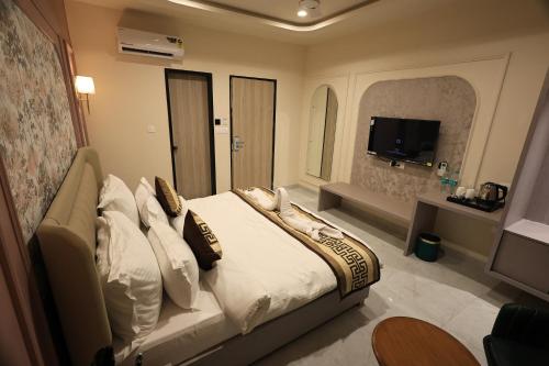 a bedroom with a bed with pillows and a television at Krishna Resort Pushkar in Pushkar