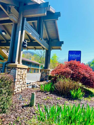 a sign in front of a building with plants at Newfound Lodge on the river in Cherokee