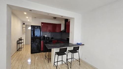 une cuisine avec des armoires rouges et un comptoir noir dans l'établissement L'Etoile à deux pas de la mer, à Boulouris-sur-Mer