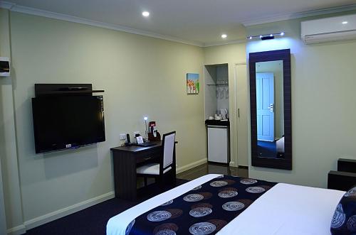 a hotel room with a bed and a flat screen tv at Park Squire Motor Inn & Serviced Apartments in Melbourne
