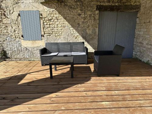 two chairs and a table on a wooden deck at La tanière de Lise in Puyravault