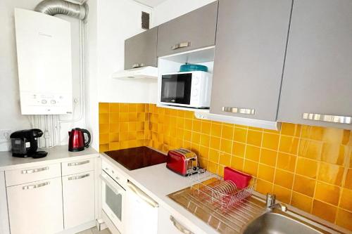 une cuisine avec des placards blancs et du carrelage jaune sur le mur dans l'établissement Apartment with balcony - sea view, à Canet