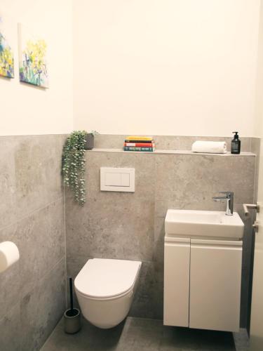 a bathroom with a white toilet and a sink at SEE & THE CITY apartments in St. Wolfgang