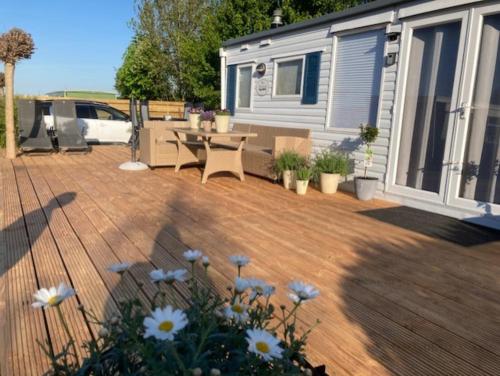 a deck with a table and chairs and a trailer at Modern Chalet nabij Ijsselmeer met mooi buitenzwembad op sfeervolle camping in Warns