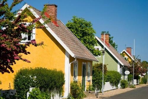 a yellow house with a brown roof on a street at Cozy Summer cottage in Tosteberga, close to the Sea in Fjälkinge