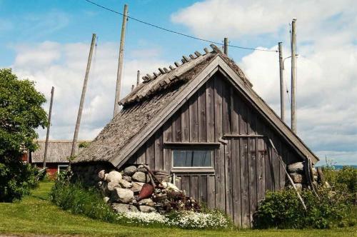 a small wooden house with a pile of rocks at Cozy Summer cottage in Tosteberga, close to the Sea in Fjälkinge