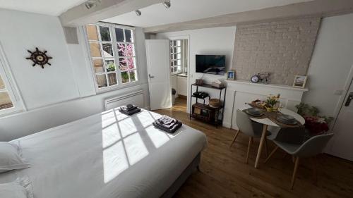 - une chambre avec un lit blanc, une table et un bureau dans l'établissement Appartement mignon en Hypercentre Honfleur - 3 étoiles, à Honfleur