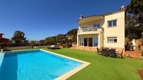 a villa with a swimming pool in front of a house at Villa Irene - Vistas al mar in Lloret de Mar