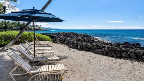 a row of chairs with an umbrella on a beach at Kona Isle B22 in Kailua-Kona