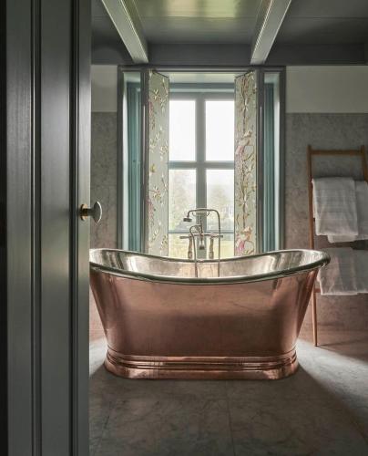 a copper tub in a bathroom with a window at Landgoed Huis te Jaarsveld in Jaarsveld