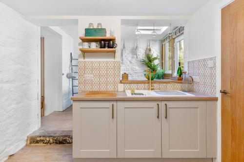 a kitchen with white cabinets and a sink at Low Tide Bedford Rd Boutiques in St Ives