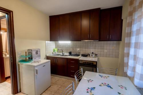 a kitchen with wooden cabinets and a table with a white appliance at Zant house in Tríkala