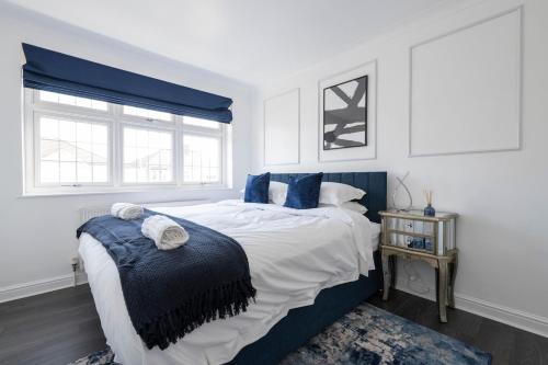 a bedroom with a large bed with blue accents at The Romford Oasis - Spacious 4 bedroom escape in Havering atte Bower