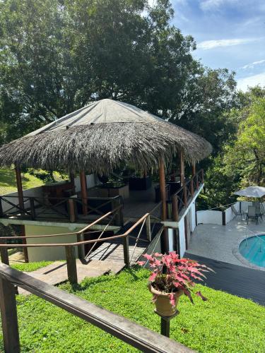a straw hut with a table and a pool at Ranchos de Chalia Panama in Portobelo