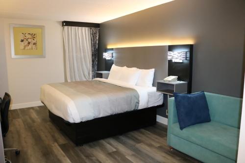 a hotel room with a bed and a blue chair at Quality Inn Bangor Airport in Bangor