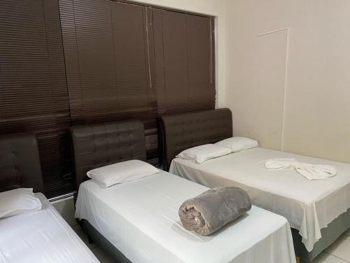 a room with two beds and a pillow on top of it at Hotel Bonanzza Coxim in Coxim