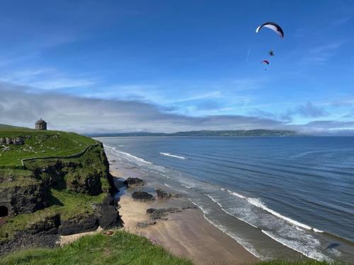 a kite flying over the ocean with a beach at The Sea Loft Castlerock. in Castlerock