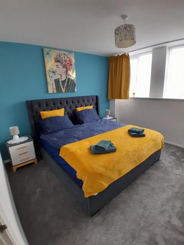 a blue bedroom with a bed with a yellow blanket at Flat in Northampton -Town Center in Northampton