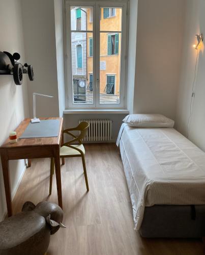 a bedroom with a bed and a desk and a window at Rebassotto in Rovereto
