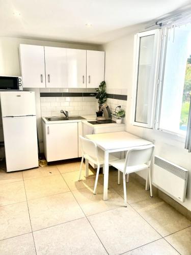 une cuisine avec une table blanche et des armoires blanches dans l'établissement studio bord de mer, à Saint-Raphaël