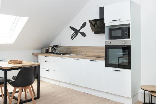 une cuisine avec des armoires blanches et une table dans l'établissement Le Jardin de Jade, à Tourcoing