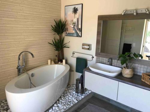 La salle de bains est pourvue d'une grande baignoire blanche et d'un lavabo. dans l'établissement Jolie Maison méditerranéenne, à Teyran