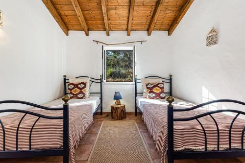 two beds in a room with a window at Monte Labarito - NatureVilla in Odemira