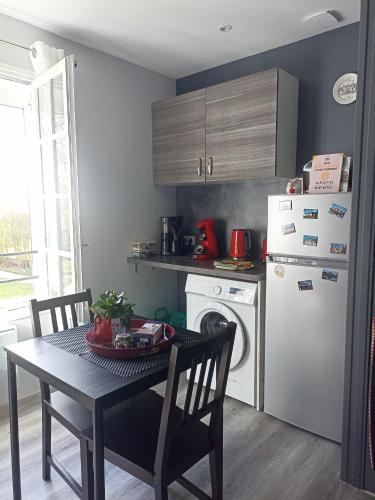 une cuisine avec une table et un réfrigérateur blanc dans l'établissement Entre 2 Châteaux, à Onzain