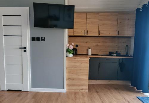a kitchen with wooden cabinets and a door open at Domki RELAXO Rewal in Rewal