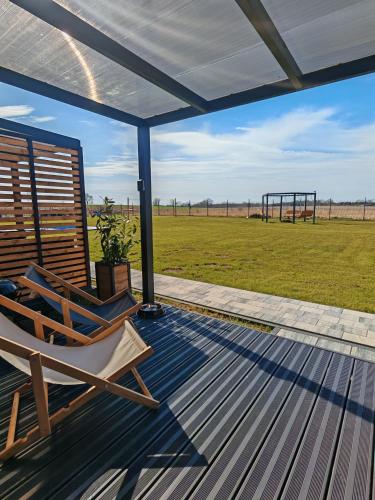 a deck with a chair and a playground at Domki RELAXO Rewal in Rewal