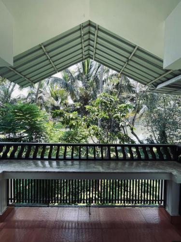 a room with a balcony with a view of trees at Maleyam Homestay Riverside in Kozhikode