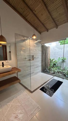 a bathroom with a glass shower and a sink at Casa das Alpinias - Trancoso in Trancoso
