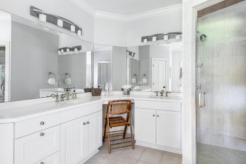 a white bathroom with two sinks and a wooden chair at 216 Glen Abbey by Akers Ellis Rentals in Kiawah Island