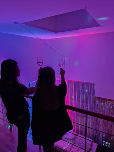 two people holding up wine glasses in a purple room at Kakumäe Raba Villa - puhkemaja basseiniga Tallinnas in Tallinn