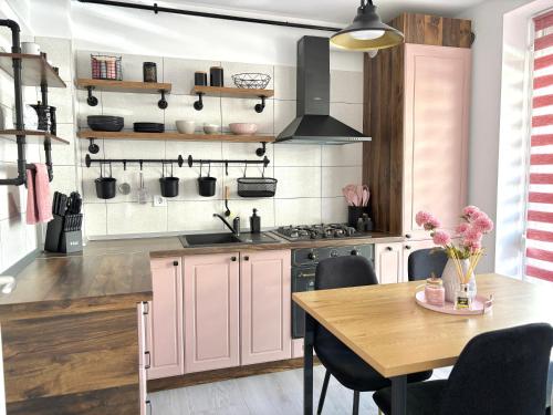 eine Küche mit rosa Schränken und einem Holztisch in der Unterkunft Wanderlust Home Pink, Rasnov Apt for 4, Wifi and Free Parking in Râșnov