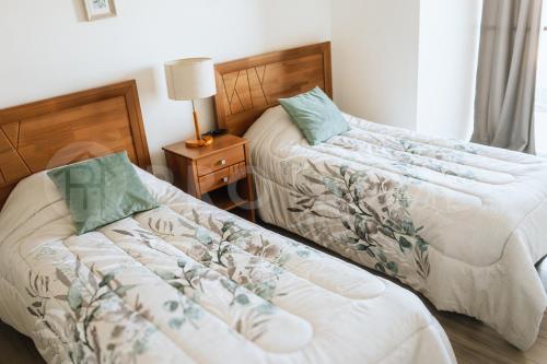 una camera da letto con due letti e un tavolo con una lampada di PRO HOME Balmaceda IV ad Antofagasta