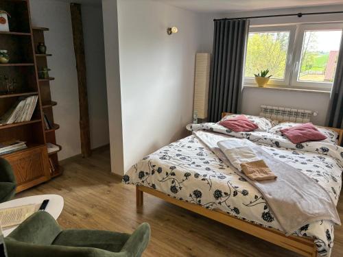 a bedroom with a bed and a chair and a window at Ranczo Popowice in Pątnów