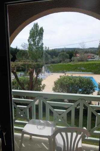 a table and chairs on a balcony with a view of a pool at Le Clos des Bruyères in Vallon-Pont-dʼArc