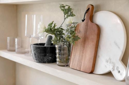 a shelf with a cutting board and a vase with flowers at Alfred's Ramsbottom - Suite Two in Ramsbottom