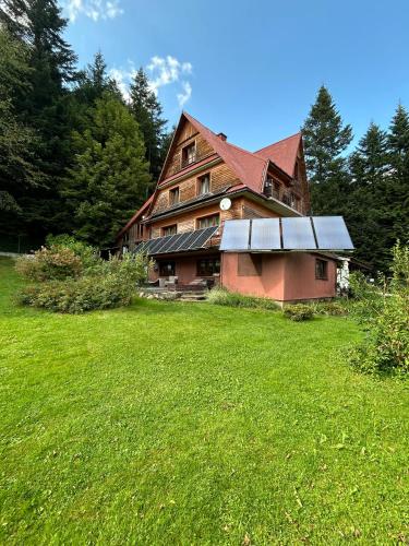 a large wooden house with a green field in front at Dom pod Cuplikiem in Zawoja