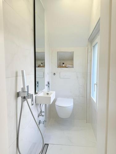 a white bathroom with a toilet and a sink at Luxrem 5 Apartments Skyline in Biel