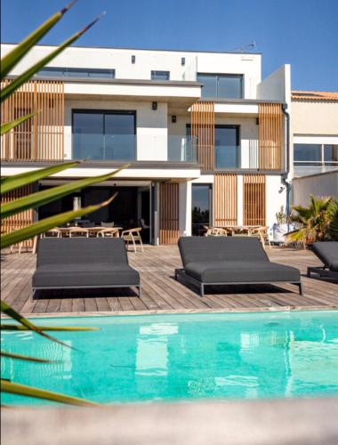 une maison avec une piscine devant une maison dans l'établissement La villa de la plage, à Mauguio