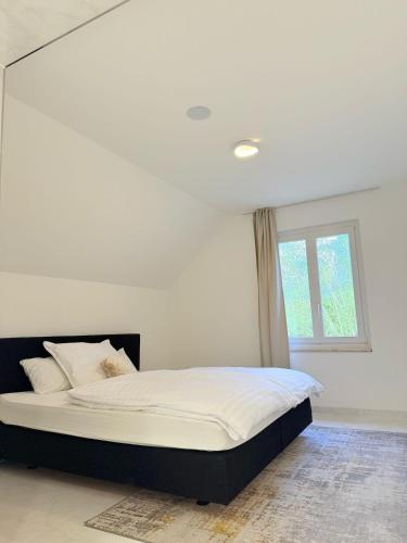a white bedroom with a large bed with a window at Luxrem 5 Apartments Skyline in Biel