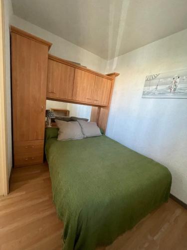 - une chambre avec un lit vert et des placards en bois dans l'établissement Appartement T3 2ème étage, à Seignosse