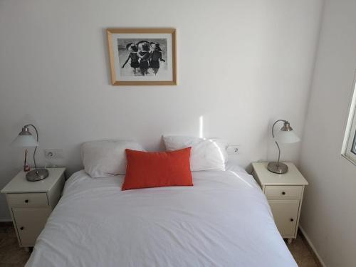 Un dormitorio con una cama blanca con una almohada roja. en Home -Cantoria Private Pool Roof Terrace, en Cantoria
