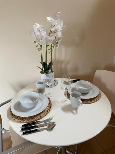 a white table with white dishes and flowers on it at Appart'Hôtel - Au Vieux Palais in Espalion