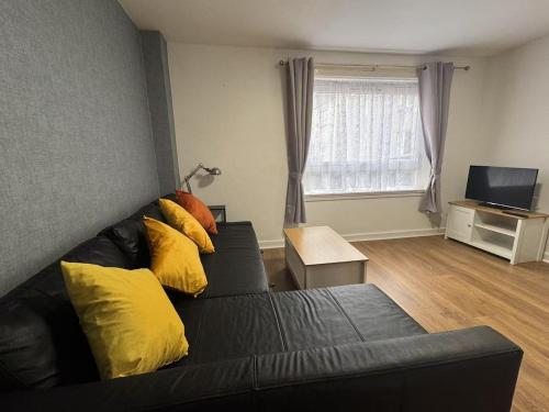 a living room with a black couch with yellow pillows at Royal Mile Escape-Free Parking in Edinburgh